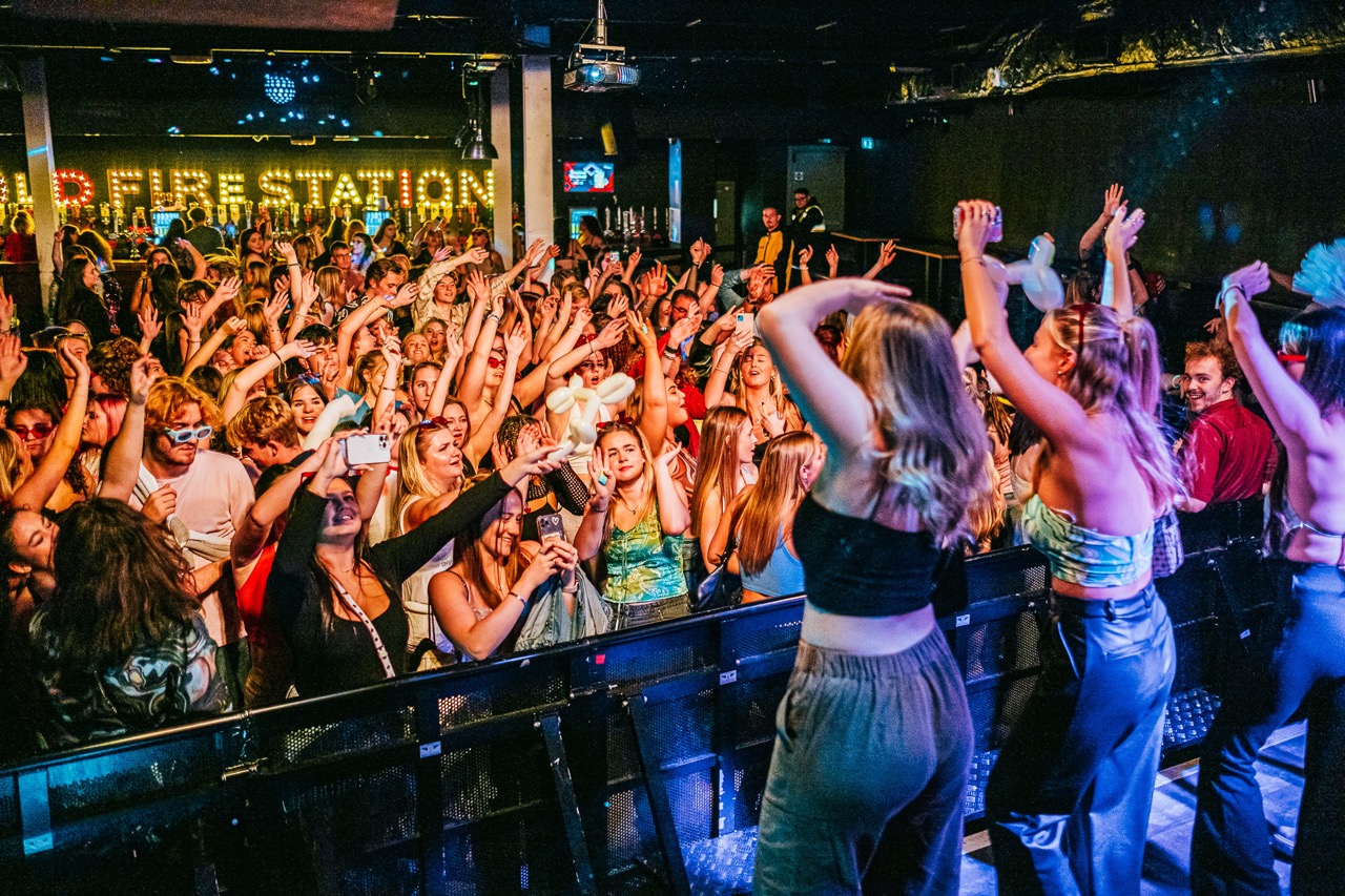 A club scene with people dancing and hands in the air