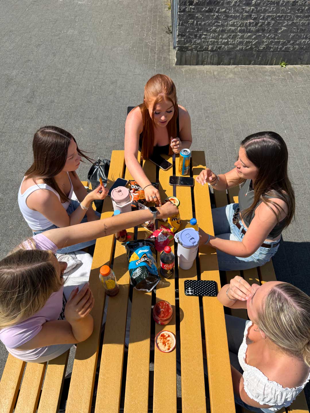 An overhead view of students sitting at a picnic bench eating food together